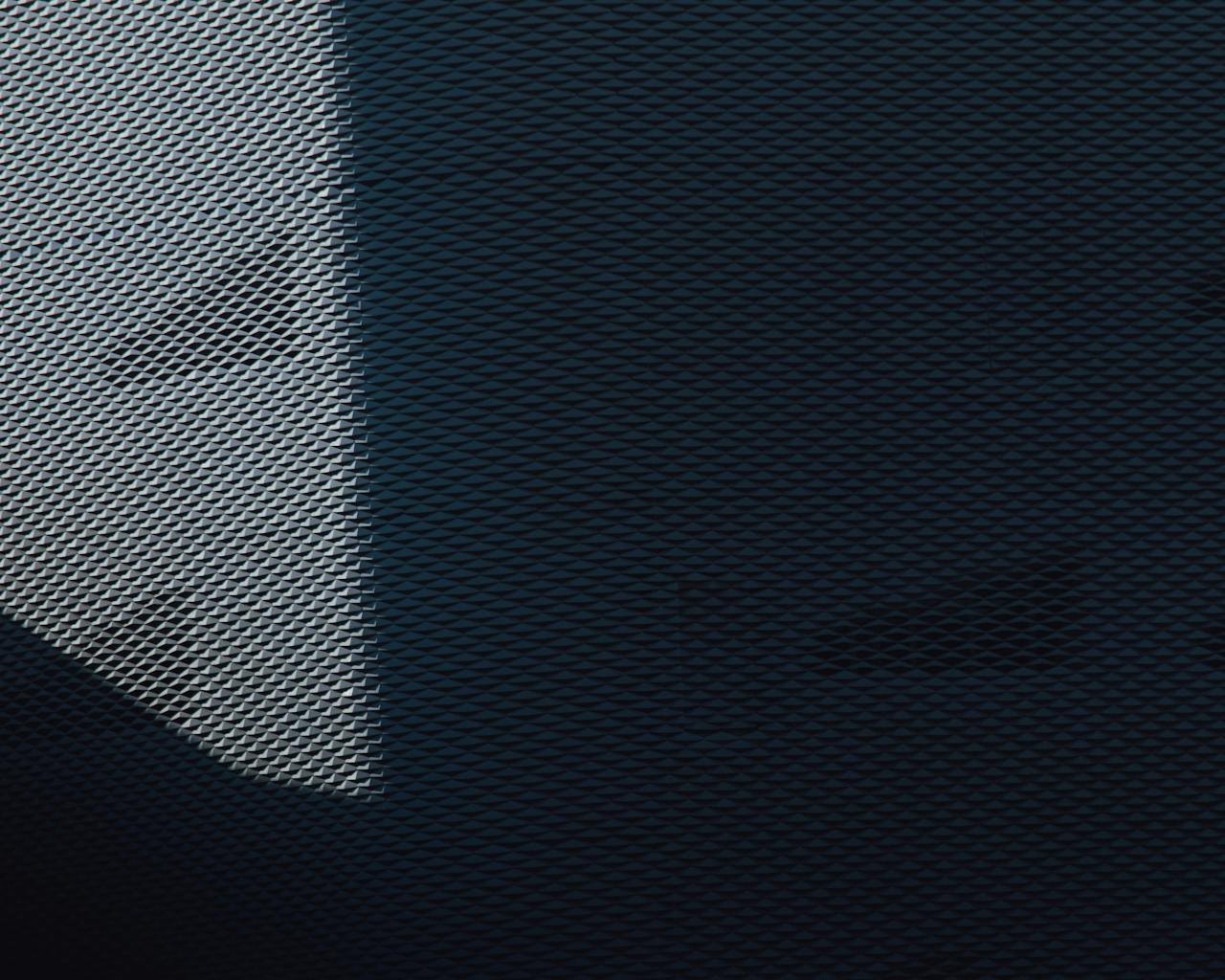 Metal mesh texture with contrasting shadow creating a striking abstract pattern and design.